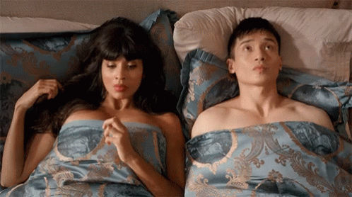 Couple from NBC Show The Good Place looking awkward in bed after sex, representing the awkwardness of the impromptu lube sex talk.